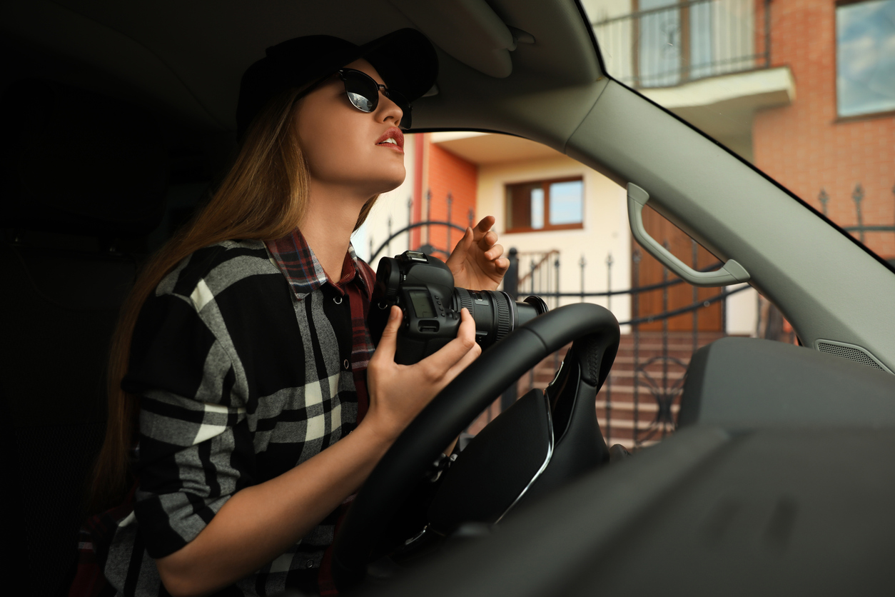 Private detective with camera spying from car
